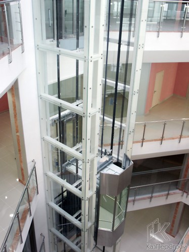Открытая шахта лифта облицованная стеклом на точечных креплениях